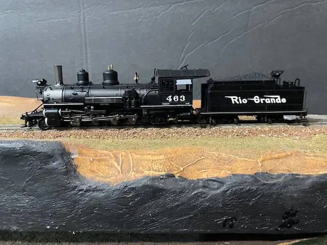 A toy train is on display in front of a wall.